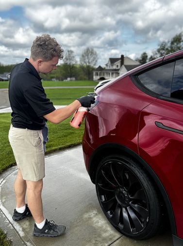 detailer wiping down a red Tesla