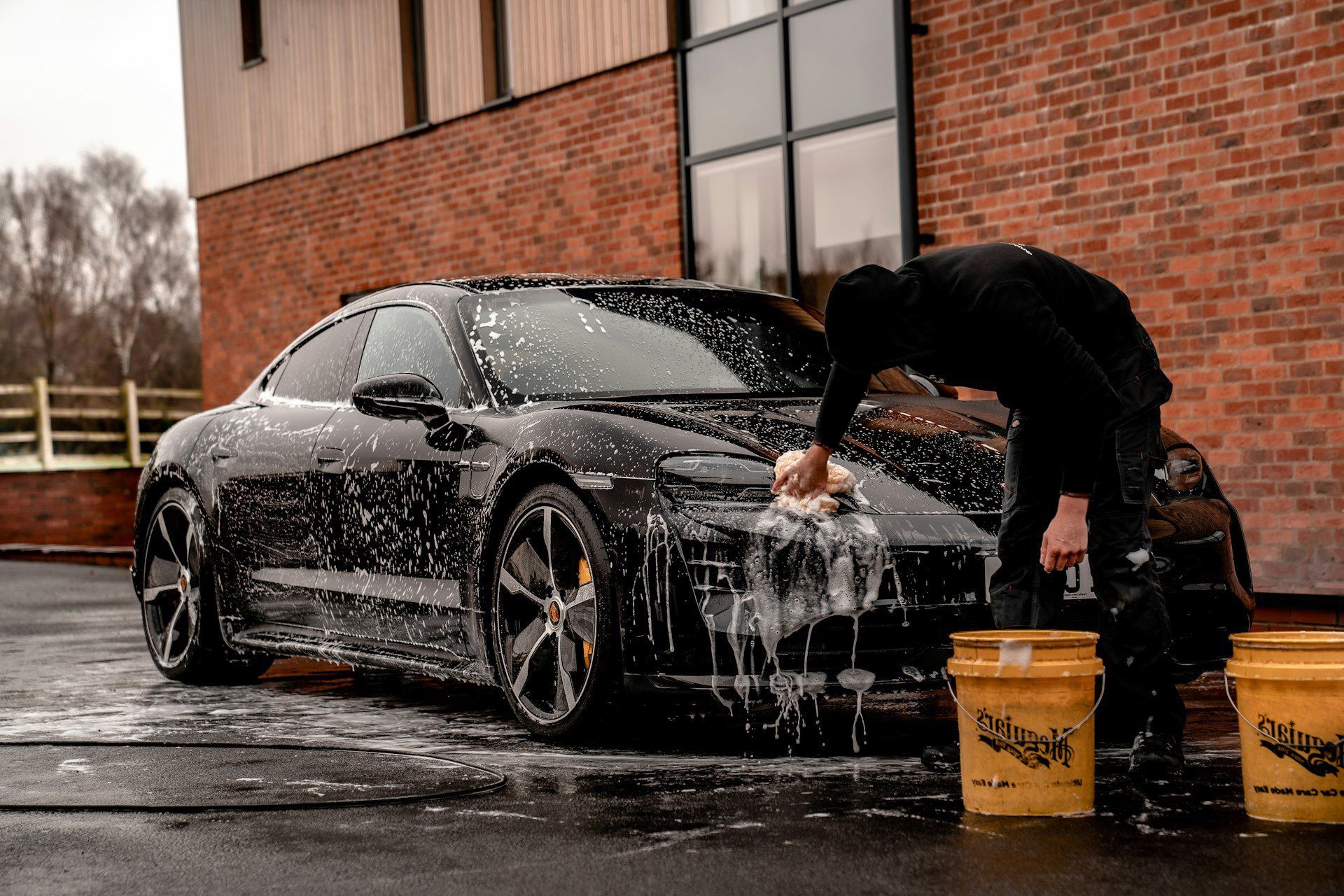 detailer foam washing a black coupe