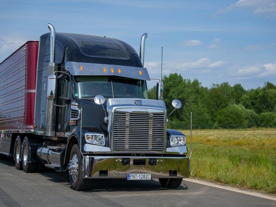 black semi truck and trailer on a rural road